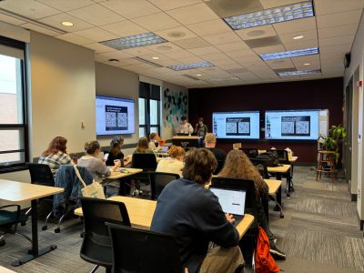 Students sit at desks looking at computer screens while transcribing historical documents.